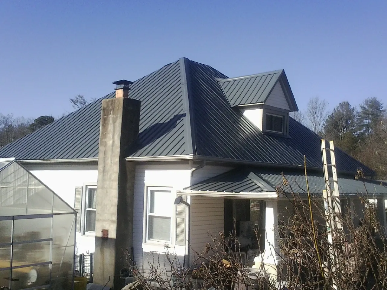 Dark blue standing seam metal roof on a white farmhouse with dormer — Slate & Tile Roof Repair by Roofing Brothers in Thousand Oaks
