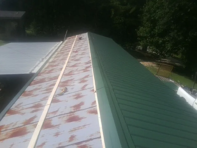 Old rusted panels beside newly installed green metal roofing — Wind Damage Roof Repair by Roofing Brothers in Thousand Oaks