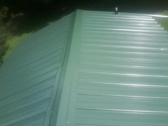 New green metal panels meeting at the ridge of a roof — Flat Roof Repair work by our crew in Thousand Oaks