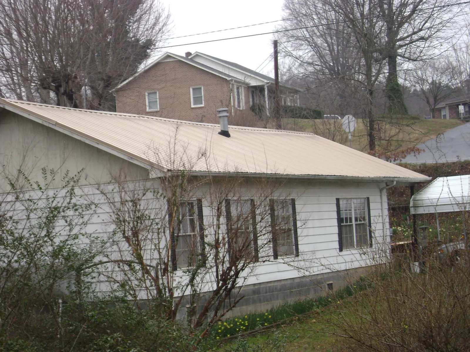 Tan metal roof on a white sided house set into a hillside — Commercial Roofing by Roofing Brothers in Thousand Oaks