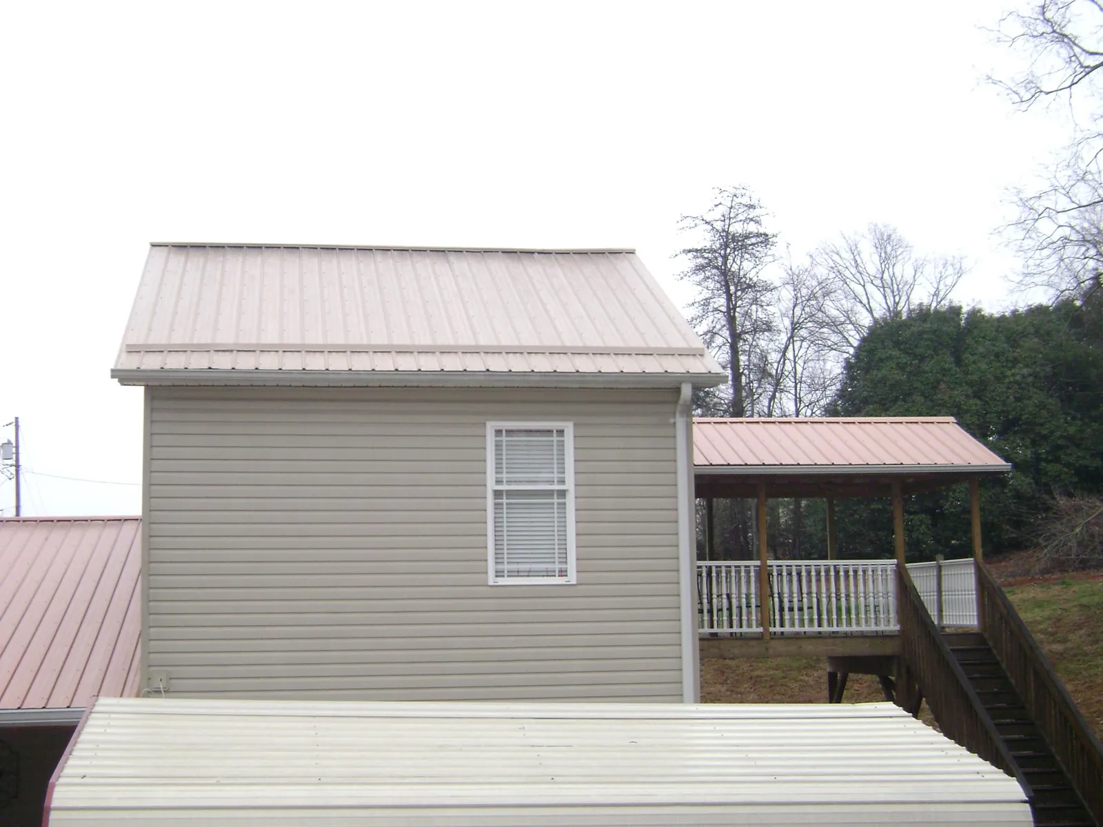 Tan metal roofs on a two story addition and attached porch, from a Roof Replacement job in Thousand Oaks