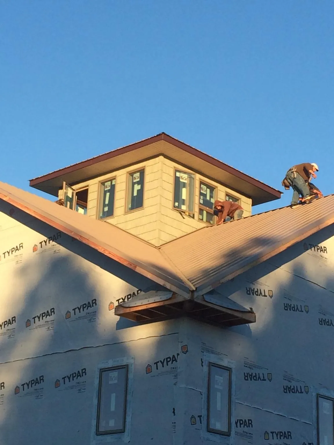 Roofers working around a rooftop cupola on a new metal roof at sunset — Roof Waterproofing in Thousand Oaks by Roofing Brothers